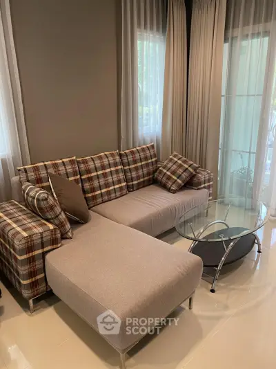 Stylish living room with modern plaid sofa and glass coffee table, perfect for cozy relaxation.