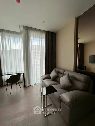 Modern living room with stylish sofa and floor-to-ceiling windows in a high-rise apartment.