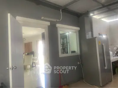 Modern kitchen with sleek refrigerator and open layout leading to dining area.