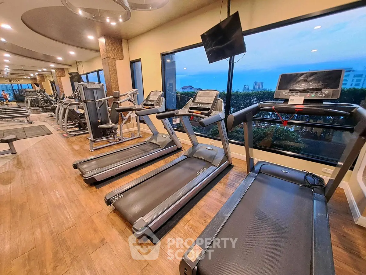 Modern gym with treadmills and large windows offering city views, perfect for fitness enthusiasts.