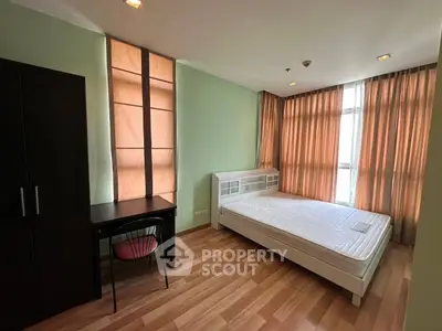 Spacious bedroom with modern furnishings and large windows for natural light.