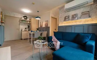 Modern living room with stylish blue sofa and dining area, featuring elegant decor and ambient lighting.