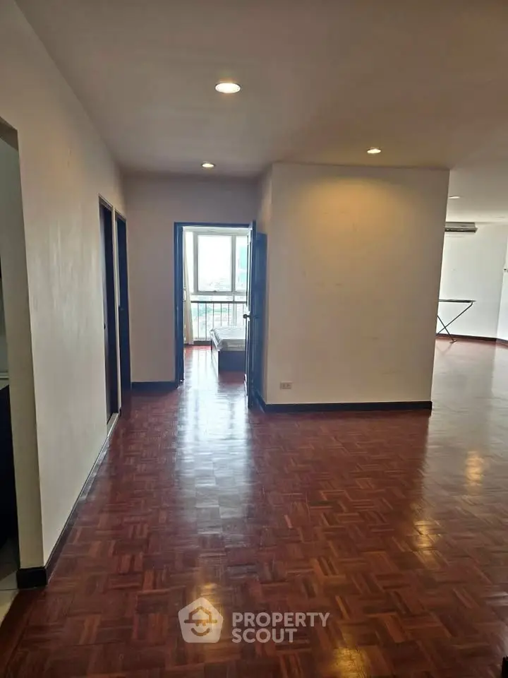 Spacious apartment with wooden flooring and natural light, featuring a balcony view.