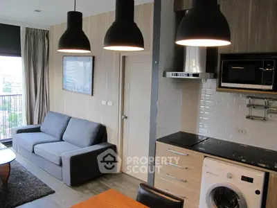 Modern living room with kitchen, featuring a cozy sofa, washing machine, and sleek lighting.