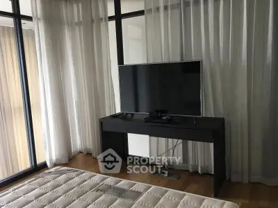Modern bedroom with large windows and a sleek TV setup, perfect for relaxation.