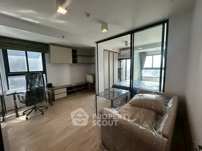 Modern studio apartment with glass partition, stylish furniture, and city view.