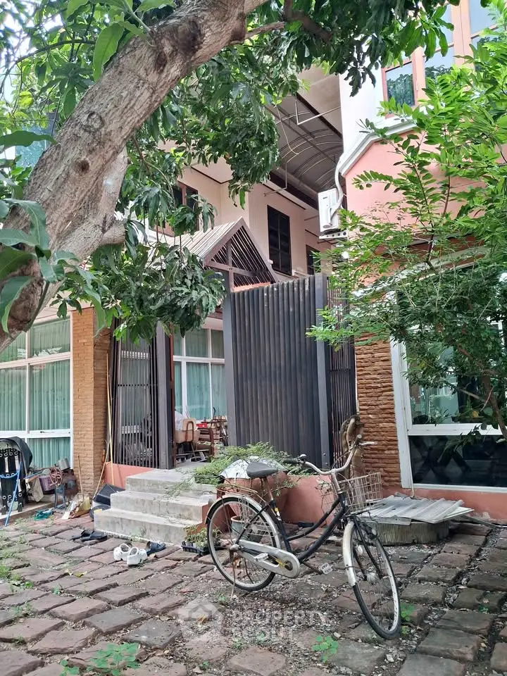 Charming residential exterior with lush greenery and vintage bicycle, perfect for nature lovers.