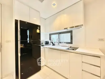 Modern kitchen with sleek white cabinets and black appliances in a luxury apartment