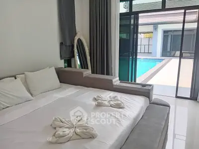Luxurious bedroom with pool view, featuring elegant decor and modern sliding glass doors.