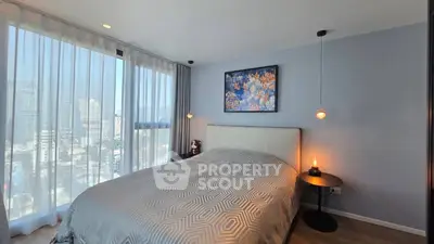 Modern bedroom with large windows and city view, featuring elegant decor and cozy lighting.