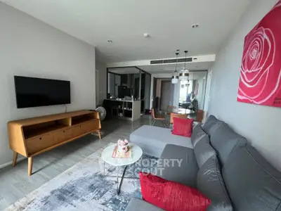 Modern living room with stylish furniture and open layout, featuring a cozy gray sofa and wall-mounted TV.