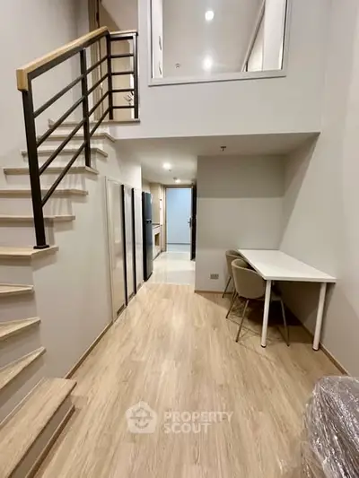 Modern duplex apartment with stylish staircase and open layout, featuring sleek flooring and contemporary design.