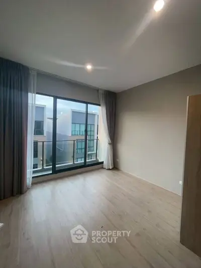 Spacious modern bedroom with large windows and balcony view in a contemporary apartment.