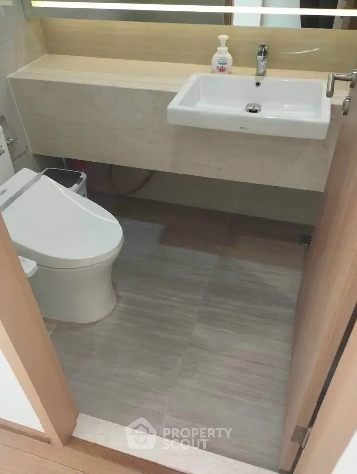 Modern bathroom with sleek fixtures and neutral tones, featuring a stylish sink and toilet.