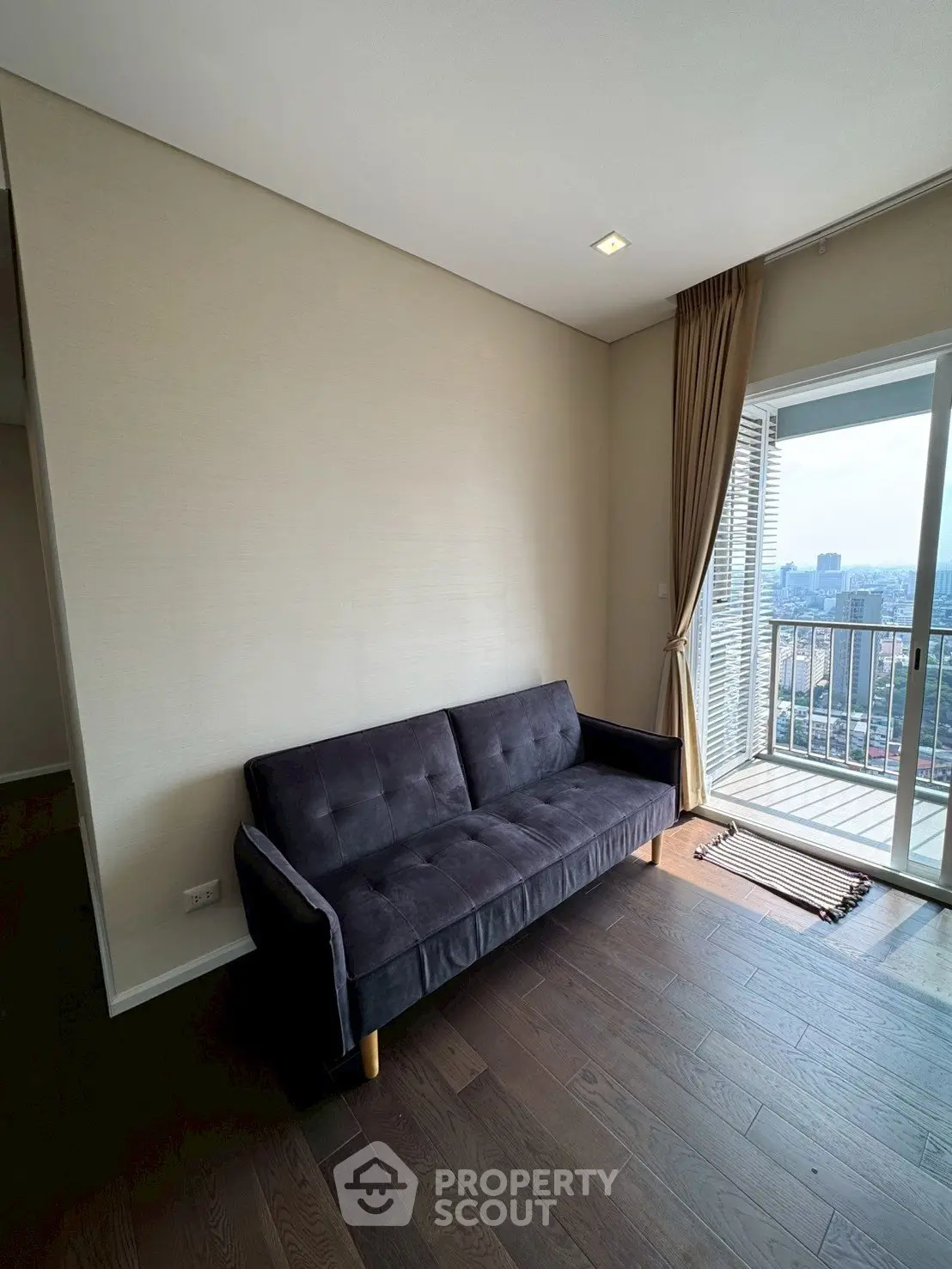 Modern living room with sleek sofa and balcony view in high-rise apartment