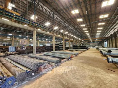 Spacious industrial warehouse with high ceilings and organized metal pipe storage.