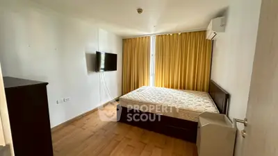 Spacious bedroom with wooden flooring, large window, and modern amenities for a comfortable living experience.