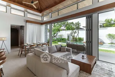 Luxurious open-plan living room with pool view and elegant dining area, featuring modern furniture and high ceilings.