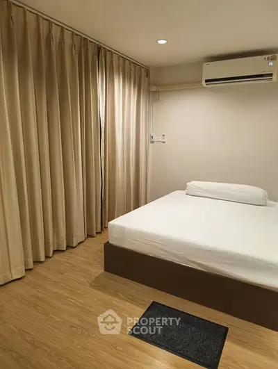 Modern minimalist bedroom with wooden flooring and air conditioning, featuring elegant curtains and cozy ambiance.