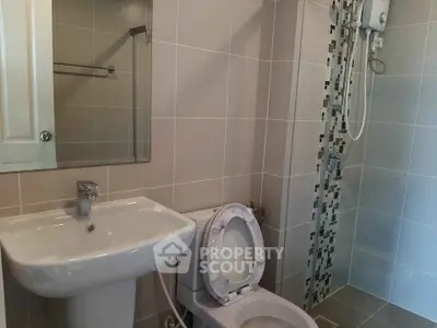 Modern bathroom with sleek fixtures and tiled shower area in contemporary apartment.