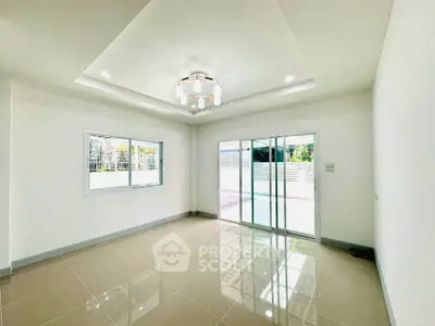 Spacious modern living room with large windows and sliding glass doors leading to outdoor area.