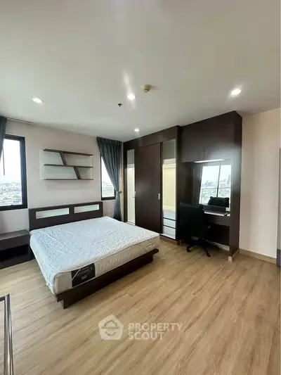 Spacious bedroom with modern furnishings and city view, featuring a comfortable bed and study area.