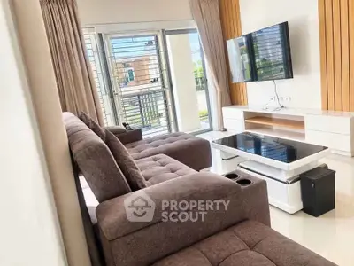 Spacious modern living room with plush sofa and wall-mounted TV, perfect for relaxation and entertainment.