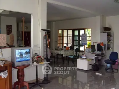 Spacious living room with dining area and home office setup, featuring large windows and tiled flooring.