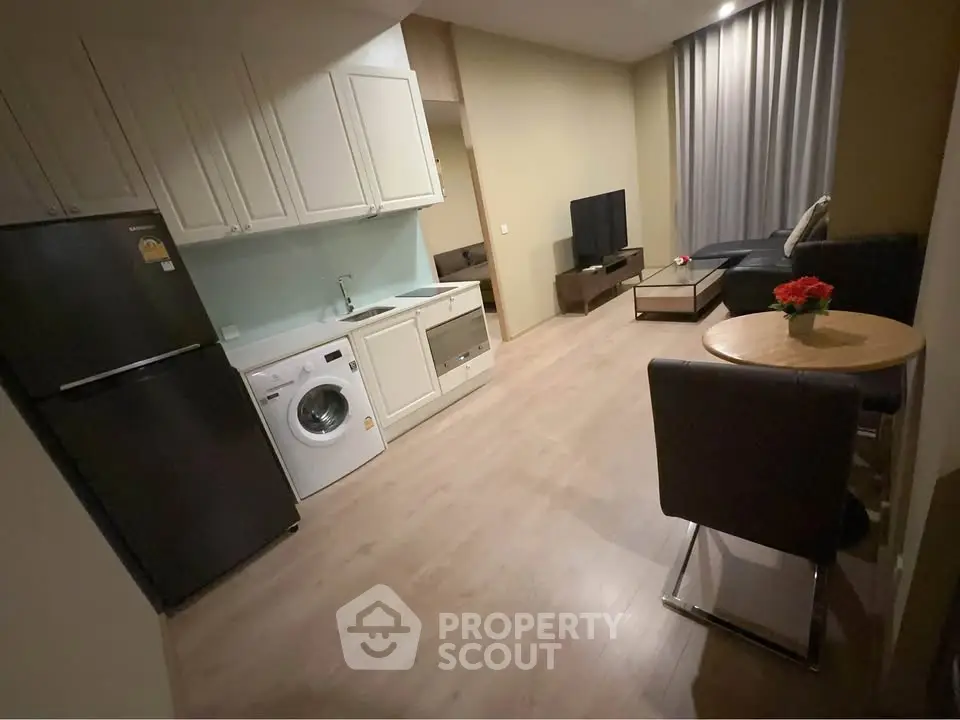 Modern open-plan living room with kitchen, featuring sleek appliances and cozy seating area.