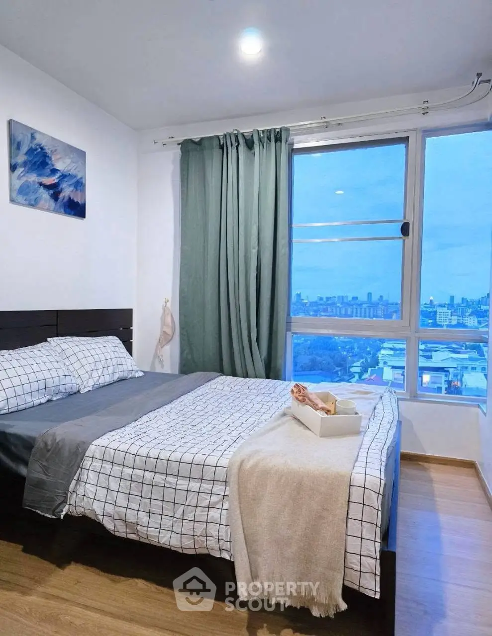 Cozy bedroom with city view, featuring a comfortable bed and large window for natural light.