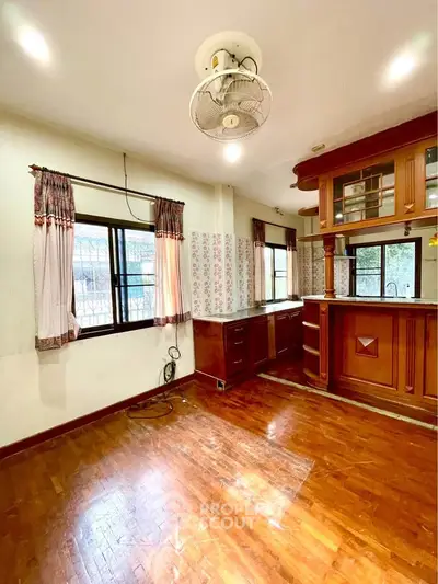 Spacious kitchen with wooden cabinets and open layout, featuring large windows for natural light.