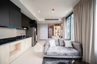 Modern open-plan living room with sleek kitchen and cozy seating area in a stylish apartment.