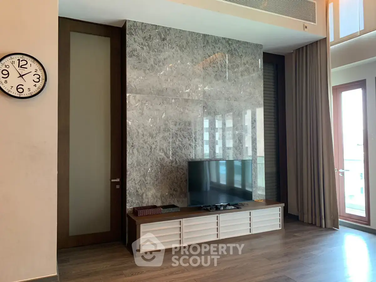 Luxurious living room with modern TV setup and elegant marble wall design.