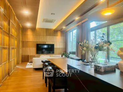 Luxurious modern living room with wooden accents and large windows offering a serene view.