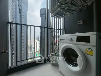 Modern high-rise apartment balcony with washing machine and city view.