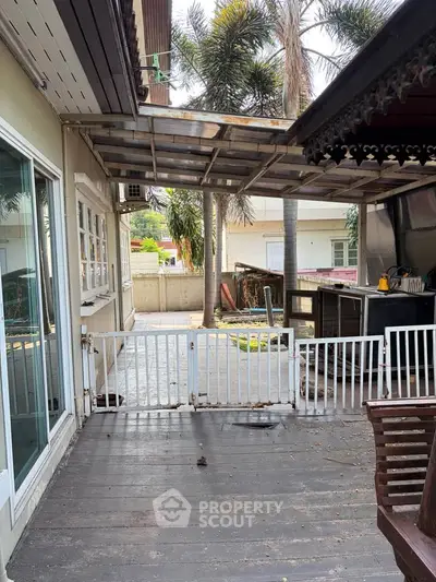 Charming outdoor patio with wooden deck and lush palm trees, perfect for relaxation and entertaining.