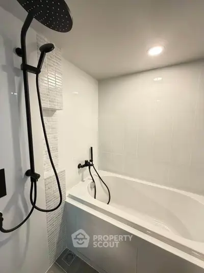 Modern bathroom with sleek bathtub and rainfall showerhead, featuring elegant tile design.