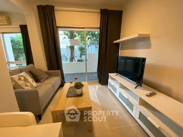 Modern living room with sleek furniture and large window leading to a balcony.