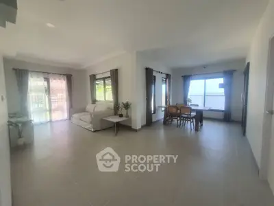 Spacious open-plan living and dining area with large windows and modern decor.