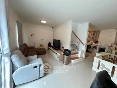 Spacious living room with modern furniture and open layout, featuring a cozy seating area and entertainment setup.