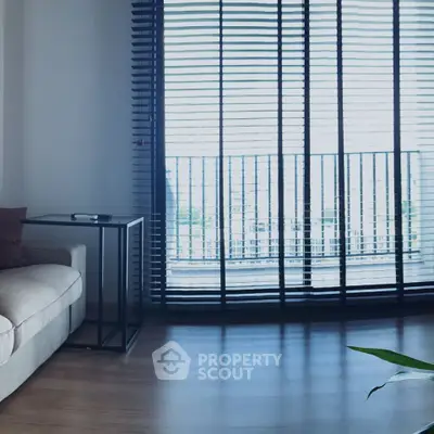 Modern living room with large windows and sleek blinds, featuring a cozy sofa and stylish side table.