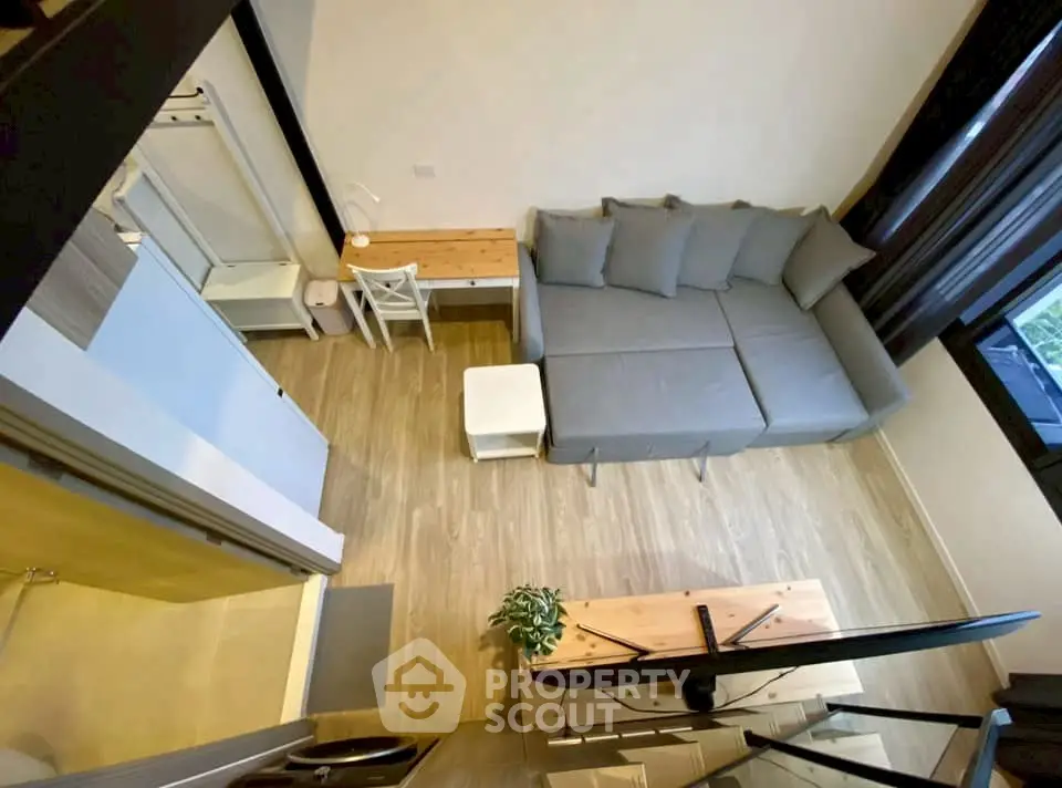 Modern living room with gray sofa and wooden flooring, featuring a cozy workspace.