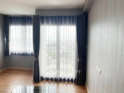 Bright living room with large windows and elegant curtains offering a stunning city view.