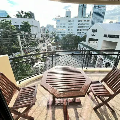 Charming balcony with wooden furniture offering a vibrant city view, perfect for relaxation and outdoor dining.