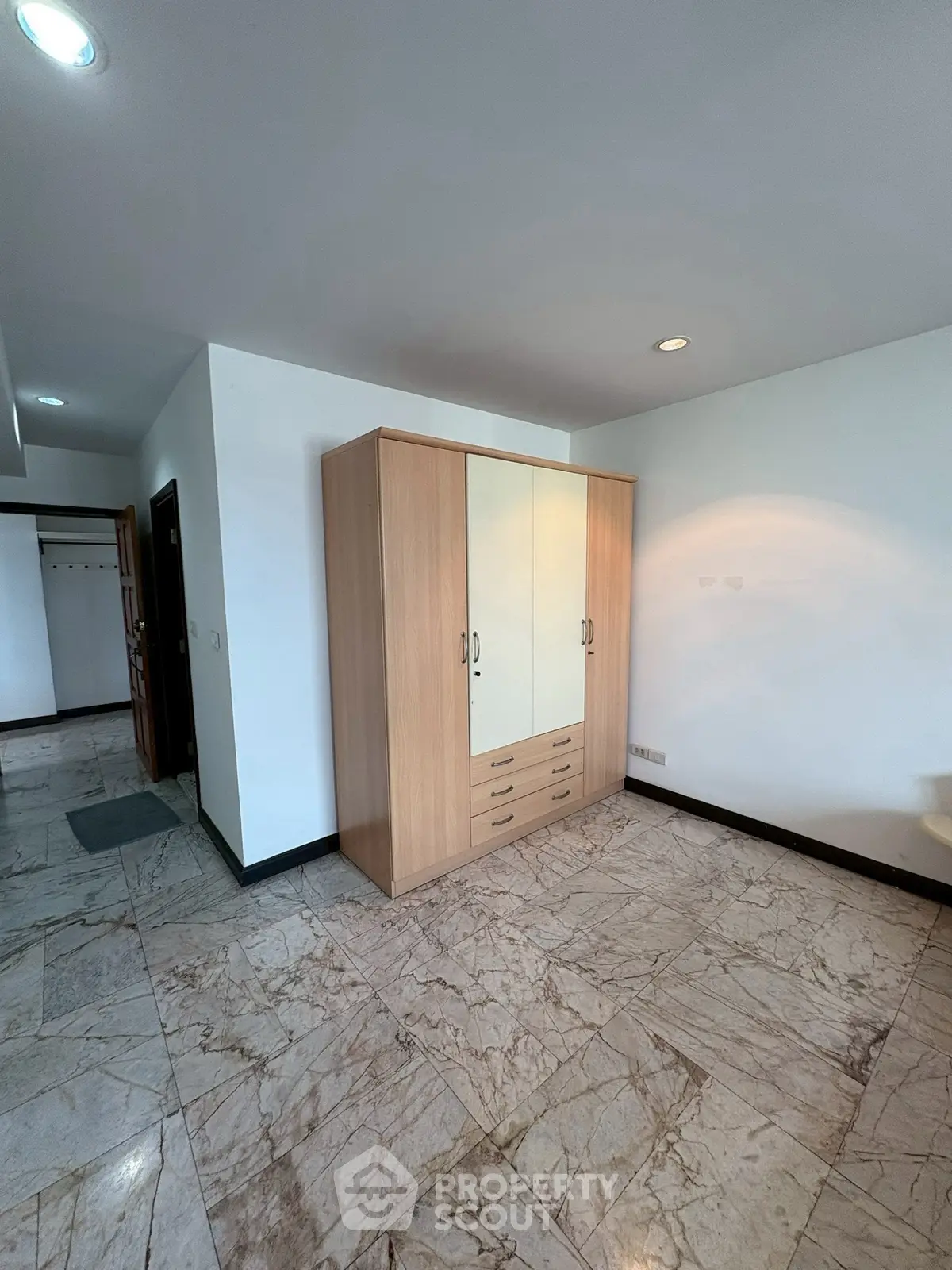 Spacious room with marble flooring and wooden wardrobe in modern apartment.
