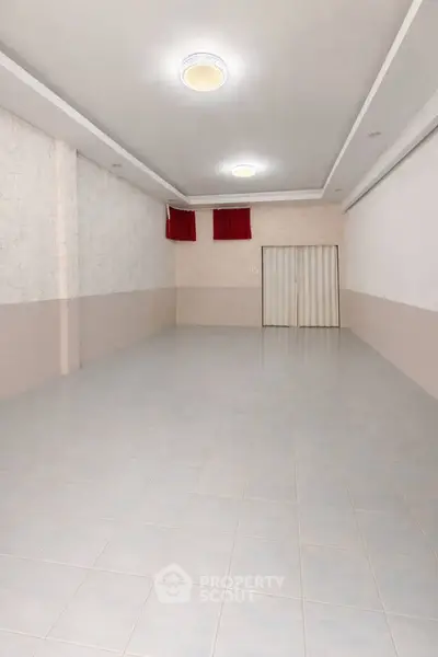 Spacious empty room with tiled flooring and modern lighting, ideal for customization.