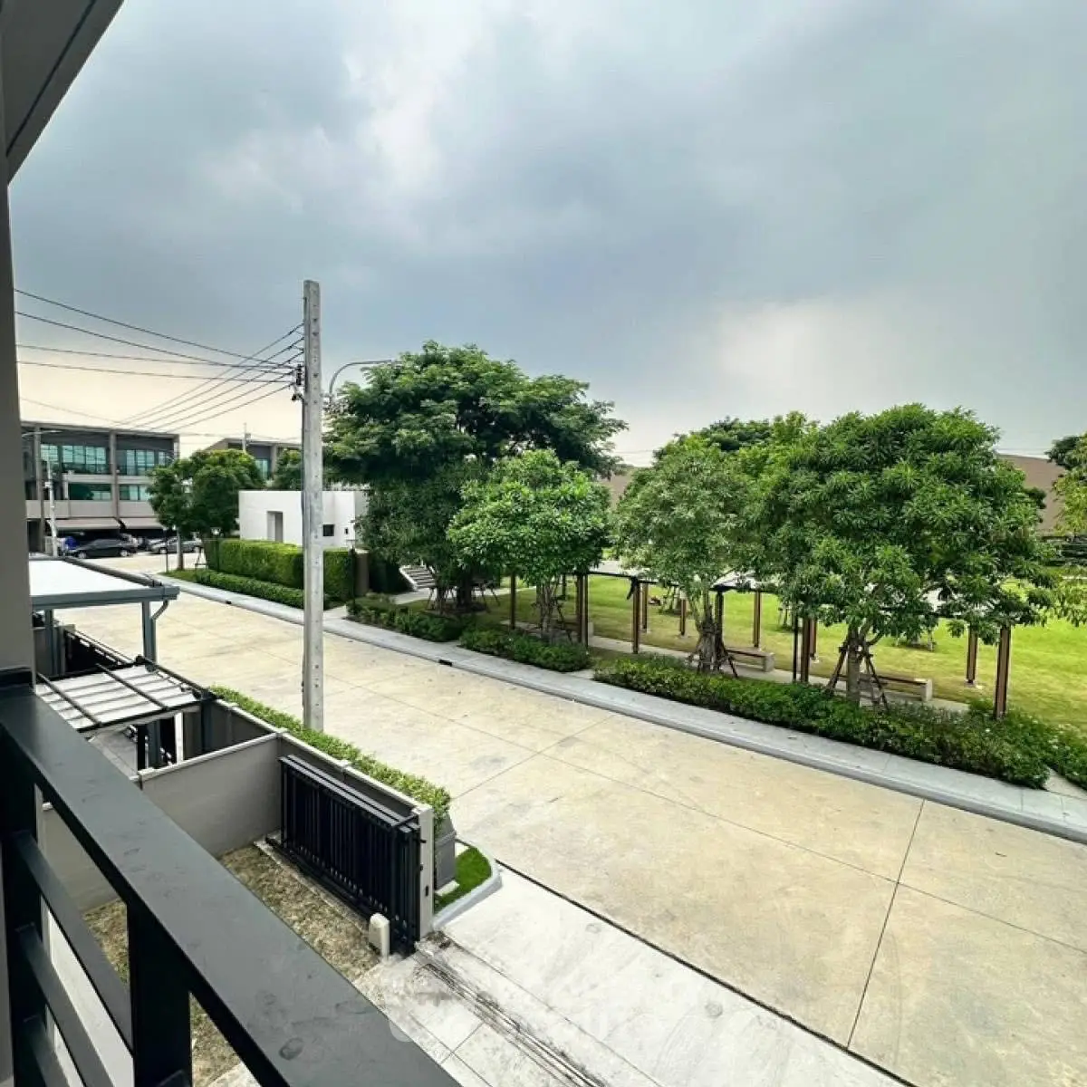 Spacious balcony view overlooking lush green trees and modern neighborhood.