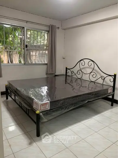 Spacious bedroom with elegant metal bed frame and large window view.