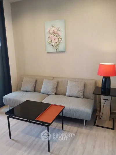 Modern living room with stylish gray sofa, elegant side table, and vibrant red lamp.