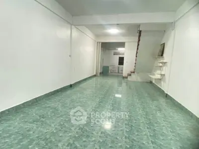 Spacious open-plan interior with green tiled flooring and staircase, ideal for versatile living arrangements.